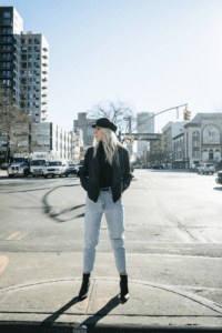 Carly Mal in Fall Fashion standing on city street with black har and jacket