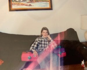 Kara from Blue Alice Space Design at 13 years old sitting on a couch with a flannel shirt