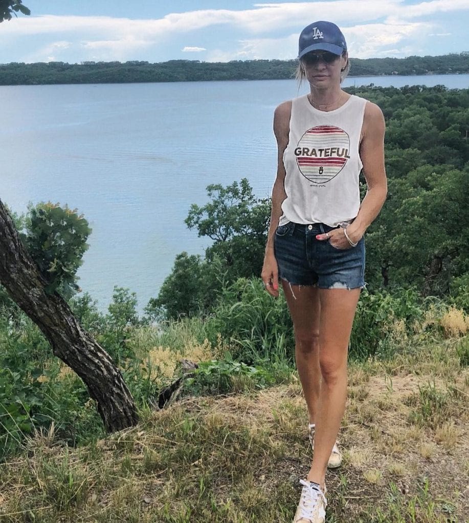 Kim (@stylebykimxo), a Kelowna-based trend setter, wearing shorts and tank top with a hat, outdoors in the Okanagan
